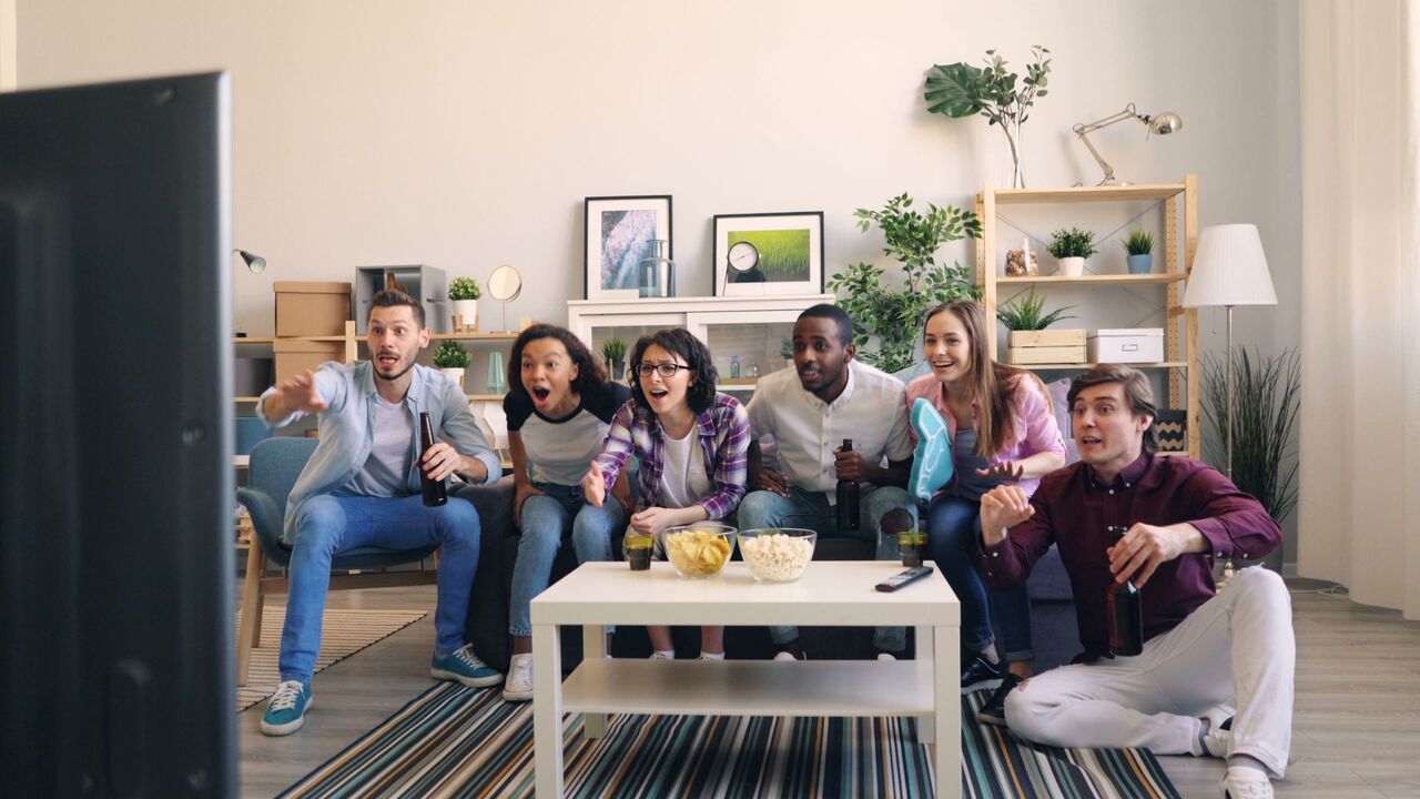 Friends cheering at a game on TV in their living room