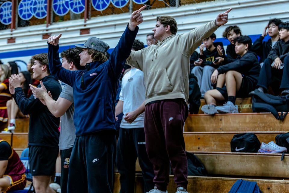 Students cheering from the bleachers at a high school basketball game